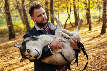 Hipster stylish guy hug his husky dog in autumn forest.Pedigree dog concept. Best friends....