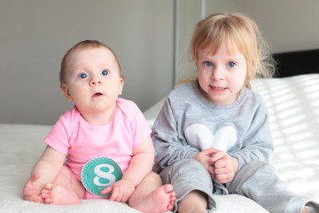 Close up portrait of Two sisters, 3 Years Old Blonde Toddler Girl and 8 Month Old Baby, Sisters, best friends, Happy Family Concept