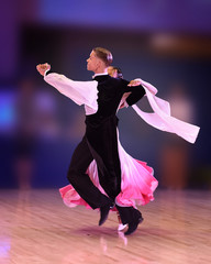 A beautiful ballroom dance couple glides across the dance floor