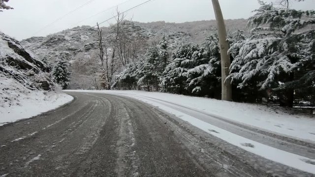 driving on snowy forest road on cold wather and frozen asphalt