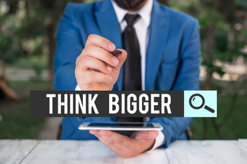Obraz premium Handwriting text Think Bigger. Conceptual photo being able to dream and visualise what you can achieve Businessman pointing with pen in empty copy space