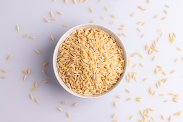 Orzo pasta, isolated on white background. Italian orzo pasta shaped like grains of rice, copy space, soft light