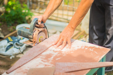 man working at home cutting tile with chainsaw on a makeshift table