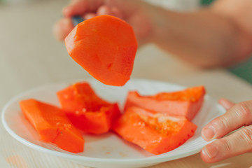  lady hand with fork in hand serving on a plate with pieces of papaya fruit