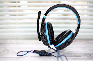 Blue headphones with a microphone on a wooden table. Photo in bright colors.