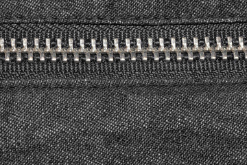 Grey jeans and silver zipper close up.  Grey fabric material texture macro zipper.