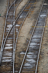 Fototapeta na wymiar Looking down on the train tracks in a railroad yard. May rows of train tracks and a switch are visible.
