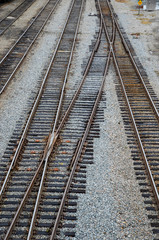 Looking down on the train tracks in a railroad yard. May rows of train tracks and switches are visible.