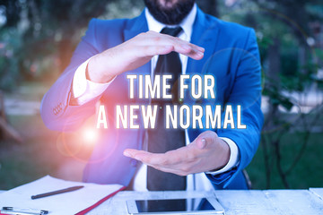 Conceptual hand writing showing Time For A New Normal. Concept meaning Make a big dramatic change Replace the expected Man in front of table. Mobile phone and notes on the table