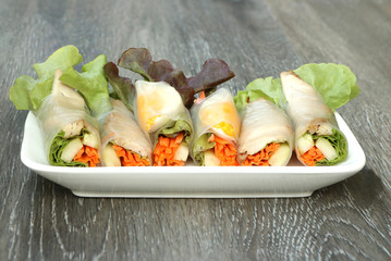 fresh vegetables spring rolls on white plate,  wood table background..