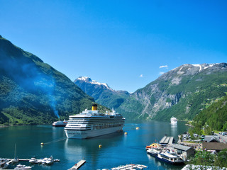 Spectacular view of Geiranger Fjord and mountains with snow, waterfalls, moored cruise ships and...