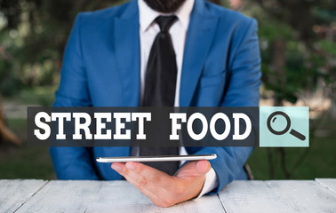 Word writing text Street Food. Business photo showcasing cooked food sold by vendors in a street or other public location Businessman with mobile phone in his hand