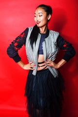 Fototapeta premium young pretty asian girl posing cheerful on red background, fashion makeup and clothers