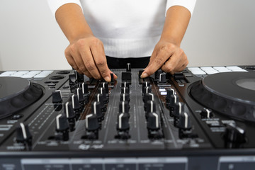 Hands of DJ mixing tracks on professional sound mixer.Fashionable rings on fingers of girl disc jockey playing music.Closeup,knobs and regulators in focus.Girl dj play music tracks at house party