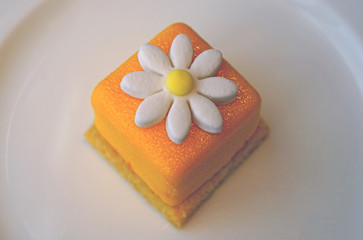 Fototapeta na wymiar Mini petit four bonbon cake with a sugar daisy flower on top