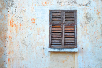 Fototapeta na wymiar Empty weathered wall and closed wooden shutters, architecture detail.