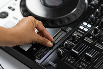 Hands of DJ mixing tracks on professional sound mixer.Fashionable rings on fingers of girl disc...