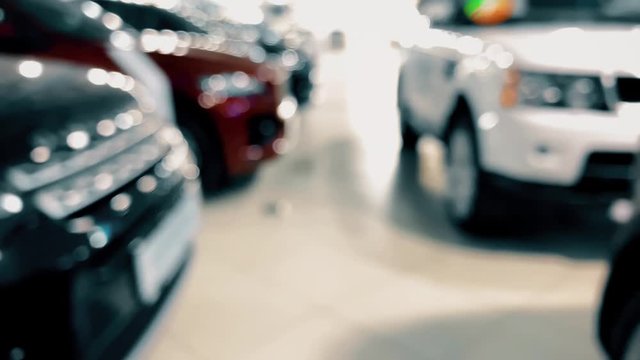 Defocused luxury new cars in a dealership showroom. POV shot