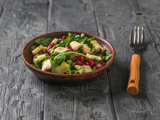 Fork and bowl with arugula, pomegranate and blue-mold cheese salad.