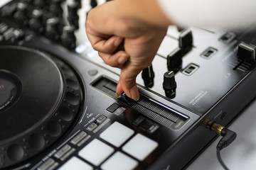 Hands of DJ mixing tracks on professional sound mixer.Fashionable rings on fingers of girl disc jockey playing music.Closeup,knobs and regulators in focus.Girl dj play music tracks at house party