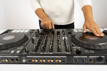 Hands of DJ mixing tracks on professional sound mixer.Fashionable rings on fingers of girl disc jockey playing music.Closeup,knobs and regulators in focus.Girl dj play music tracks at house party