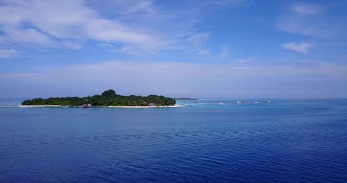 Paradise tropical islands with lush vegetation surrounded by blue turquoise lagoon under a purple sky with clouds hanging over Maldives archipelago  