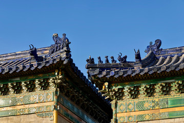 The roof of an ancient Chinese temple with blue ceramic tiles and mythical figures. The temple roof against the blue sky. Temple of Heaven, Beijing. Asian architectural background