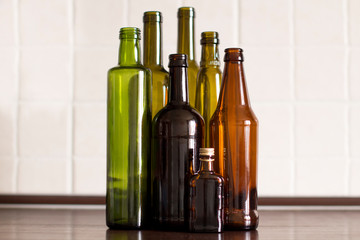 green and brown empty glass liquor bottles in a row on a kitchen table