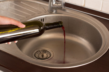 young woman dumping wine from a bottle down the drain