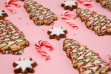 Sweet food for Christmas - biscuits with candy canes and almond stars - pink background with shallow focus