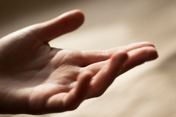 hand of a young woman reaching out on beige background