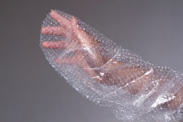 young womans hand covered in transparent air bubble plastic wrap
