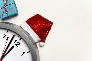 Clock with christmas hat and little box with a gift on a white background. Copy space