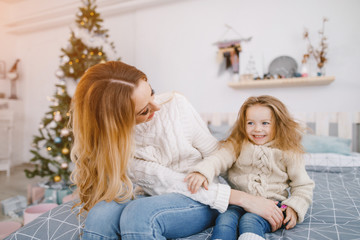 mother and daughter playing on the bed in a room decorated for the holidays