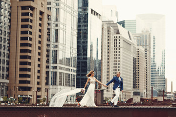 Beautiful bride in a long white dress. Handsome fiance in a blue suit. Couple in a big city