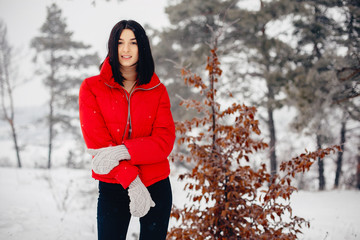 Cute girl walking in a winter park. Woman in a red jacket