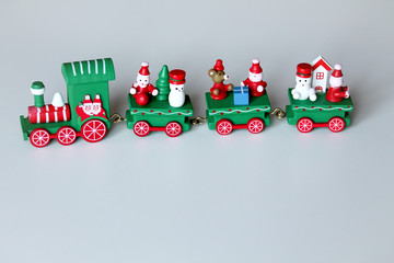 Green festive wooden train on white background with copy space. Christmas and New Year toy with figures of snowman, mouse or rat, and gnomes. Greeting card, poster template.