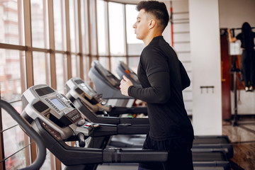 Sports man in the gym. A man performs exercises. Guy in a black t-shirt