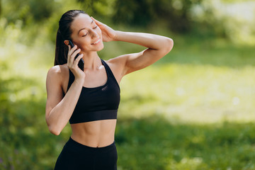 Cheerful woman standing in the park talking a phone outdoor. - Image