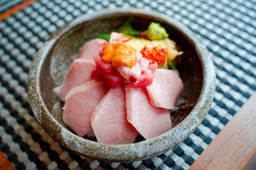 Close up premium  Donburi slice raw Otoro Maguro Japanese rice bowl. This menu on top of salmon eggs and wasabi,serve in Japanese traditional cwramic bowl  put on wooden table in Japanese restaurant.