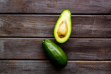 Avocado - ripe and bright, cutted in half - on dark wooden background top view copy space