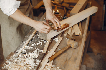 Man working with a wood. Carpenter in a white shirt