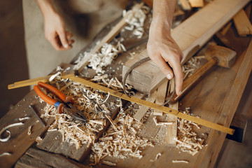 Man working with a wood. Carpenter in a white shirt