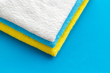 Clean towels - stack of laundred linen - on blue background top view copy space