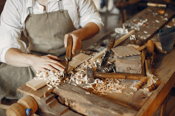 Man working with a wood. Carpenter in a white shirt