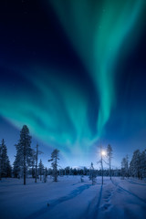 Moon and Northern Lights above Pallas fells with fresh snow at winter night in Pallas-Yllästunturi...