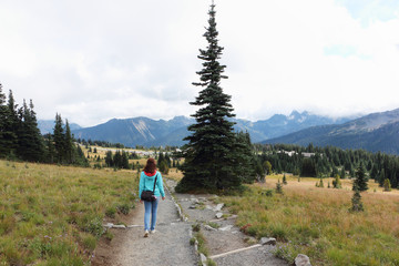 Woman walking along a mountain trail near Mount Rainier, Washington State, USA