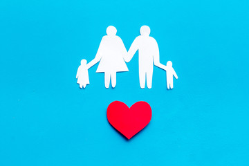 Happy family concept. Heart icon near mom, dad and childrens cutout on blue background top view copy space