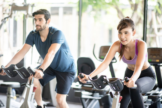 Young healthy woman and man bike cardio at the gym.