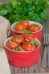 Vegetarian food: Mediterranean style baked tomatoes stuffed with feta cheese, chickpeas and herbs in red pan on wooden background